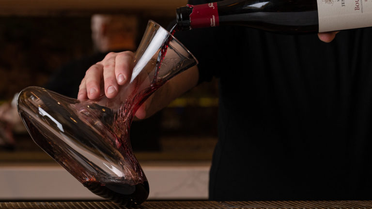 Bartender pouring red wine in a decanter