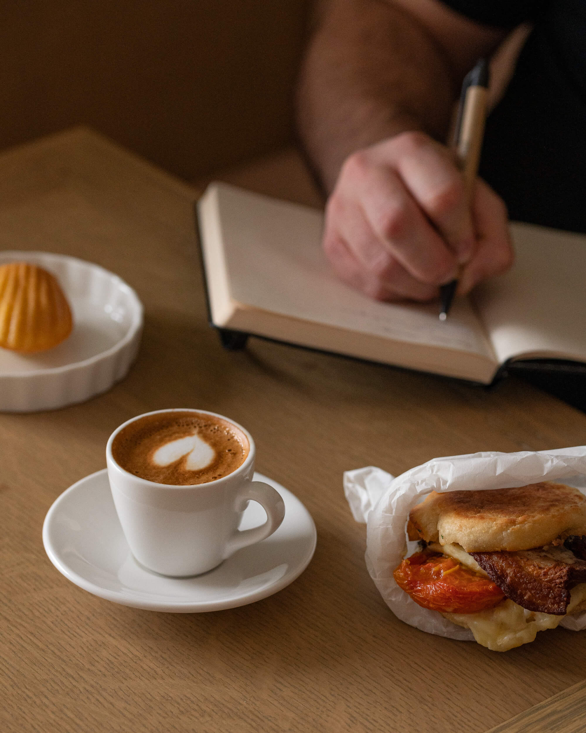 Person writing in a notebook while enjoying breakfast items